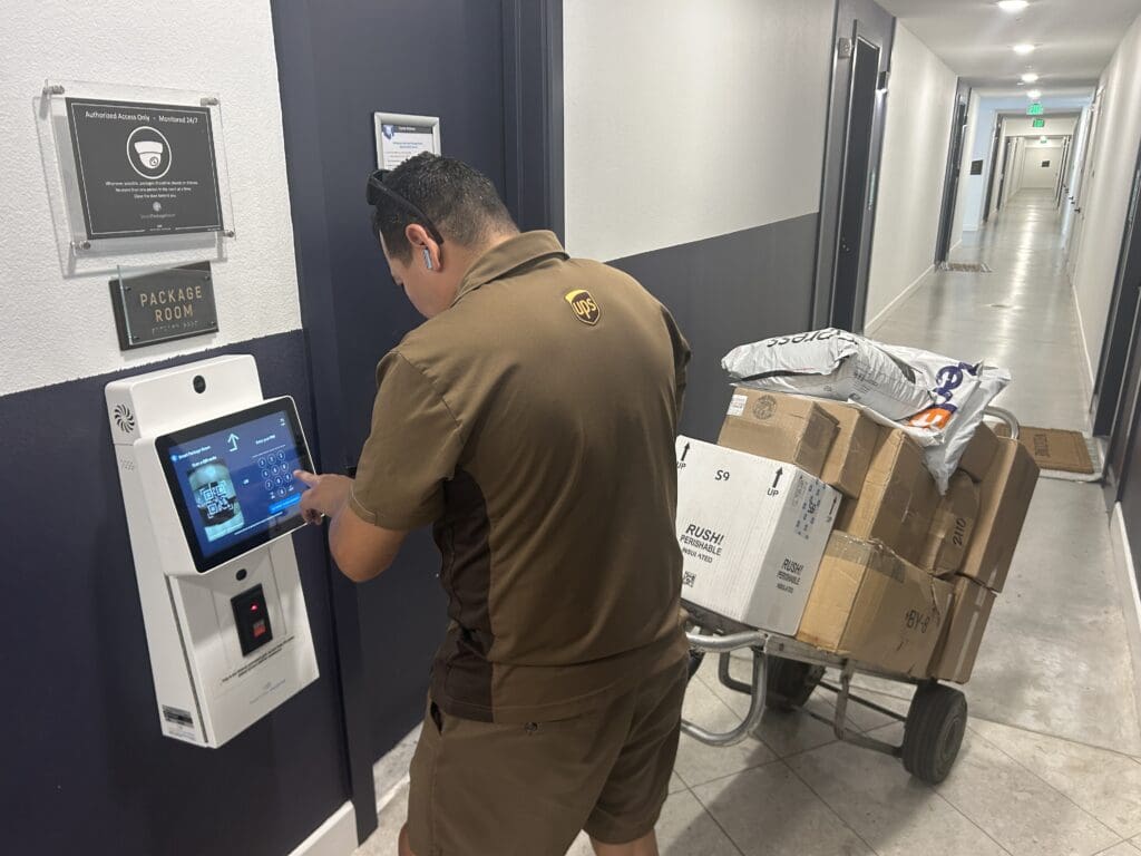 A UPS deliveryman uses a tablet to drop off packages in a SmartPackageRoom.