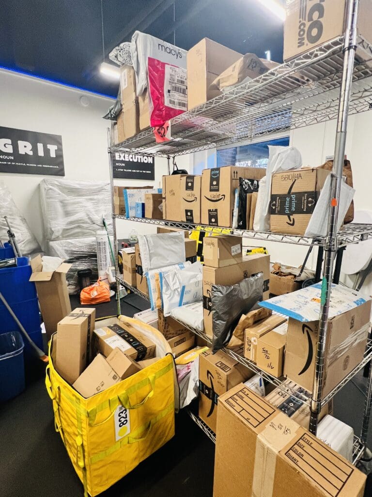 A mailroom filled with stacked boxes and other mail.
