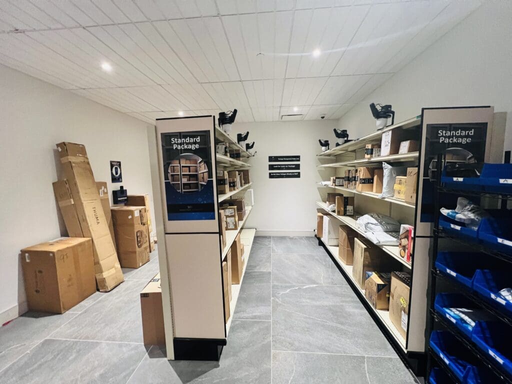 The Smart Package Room solution with organized shelves storing packages of all shapes and sizes, showing a secure and efficient package delivery system for multifamily apartment buildings.