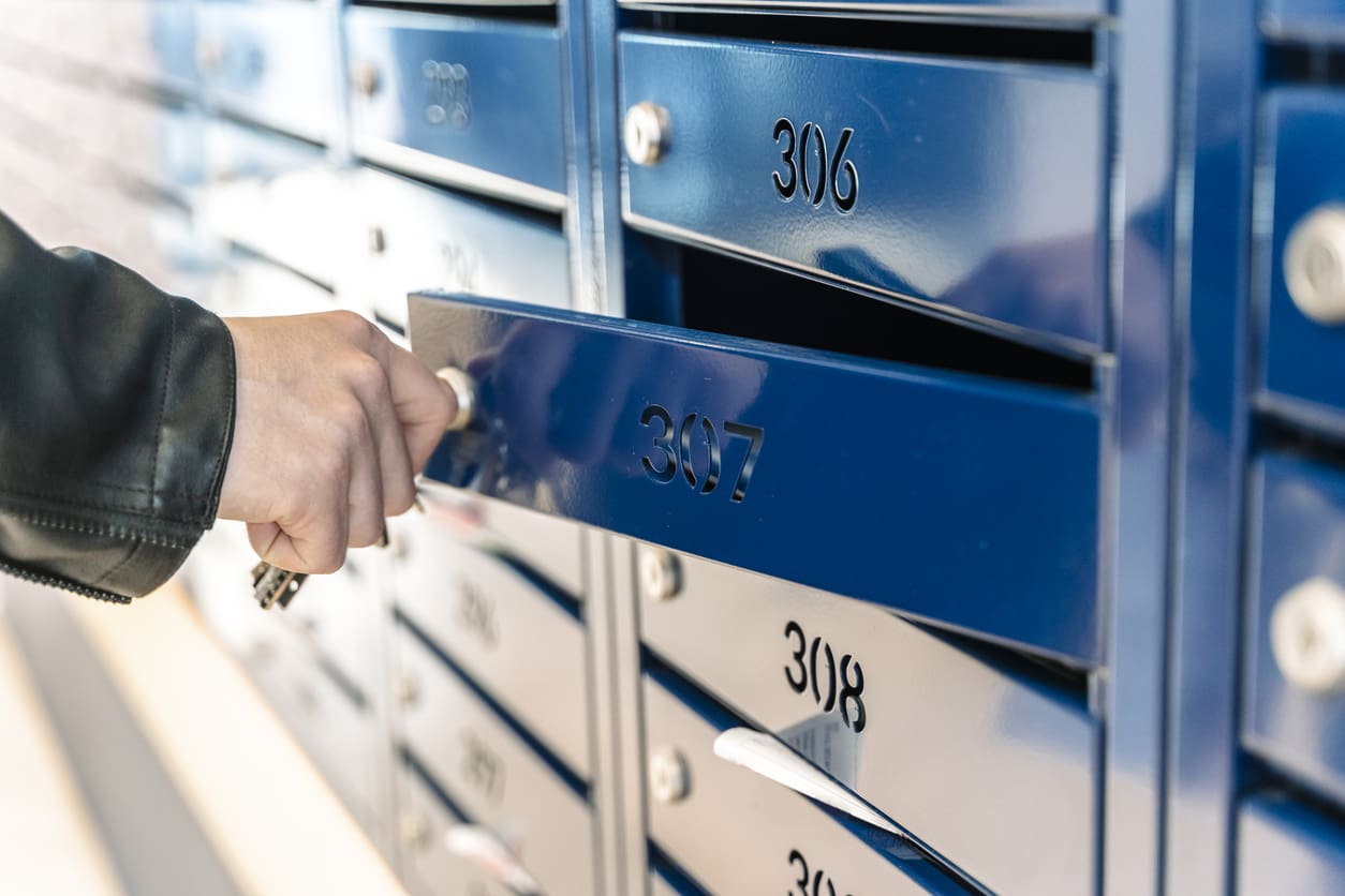 Resident unlocking a numbered apartment mailbox, symbolizing traditional delivery methods being replaced by advanced technology for apartment mailrooms.