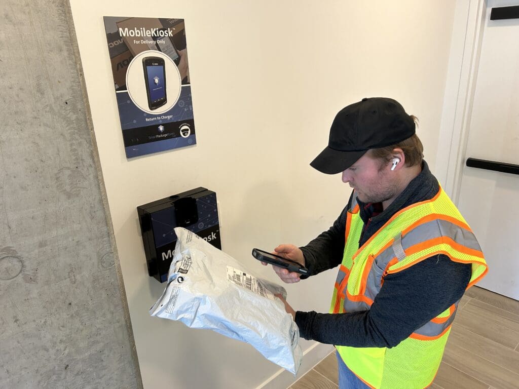 Courier scanning a package with the MobileKiosk device, demonstrating how Smart Package Room technology helps automate package management in multifamily buildings