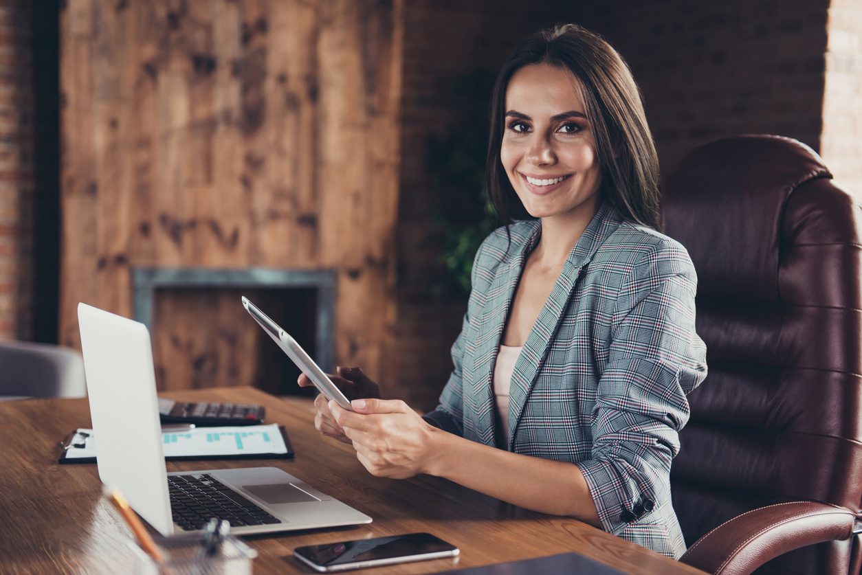 Female operations manager reviewing documents at her desk with a laptop, representing multifamily property professionals.