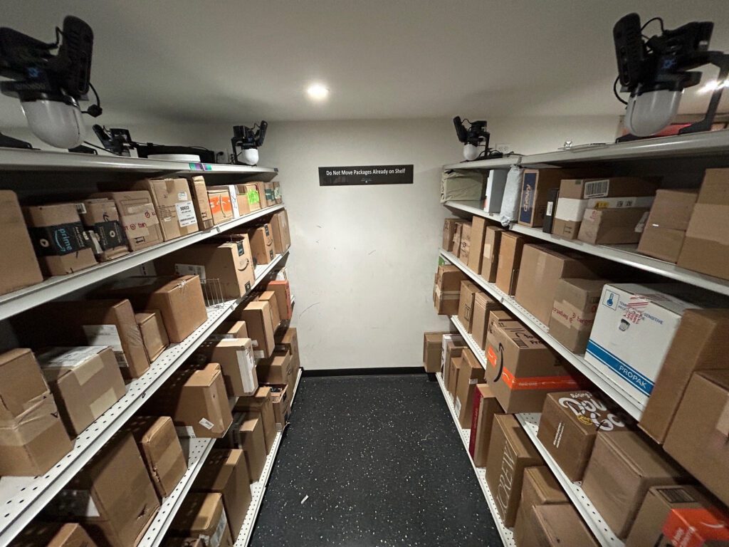 Open shelving system inside a Smart Package Room solution displaying packages of various sizes tracked by the Amoeba module.