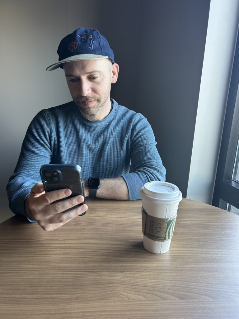 Male resident checking his phone at a table, representing the modern renter experience with Smart Package Room notifications.