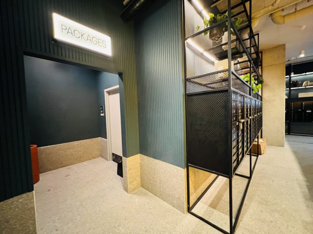 Package room with organized open shelving next to a row of traditional mailboxes
