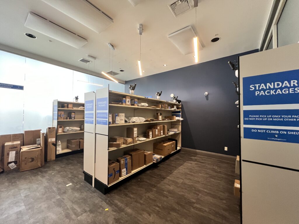 Interior of a Smart Package Room showing the must-have features in a package management system, including labeled standard package shelving zones and oversized packages along the wall