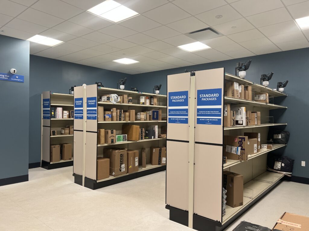 Neatly organized Smart Package Room layout with floor-to-ceiling shelving on both sides filled with resident packages, showcasing improved mailroom service in a high-rise setting