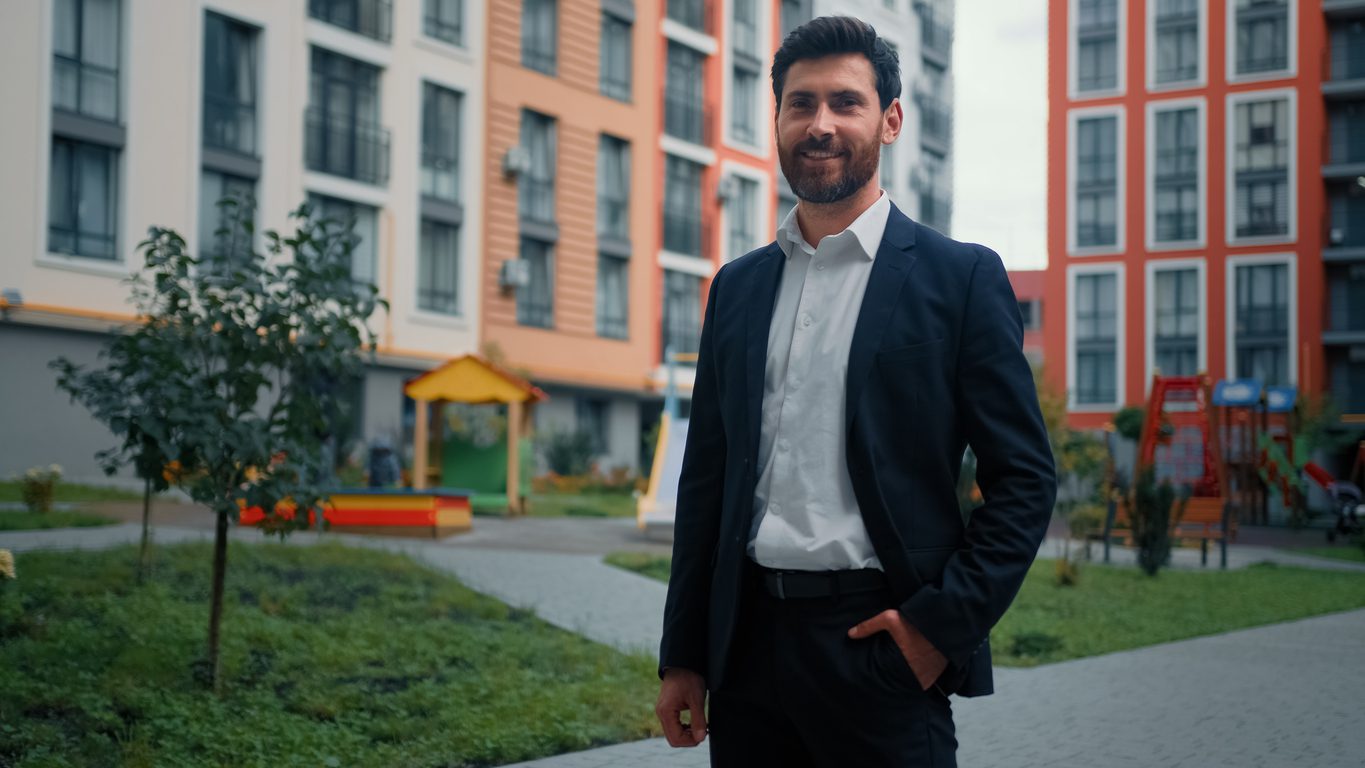 Multifamily property manager standing in the courtyard of a modern apartment community