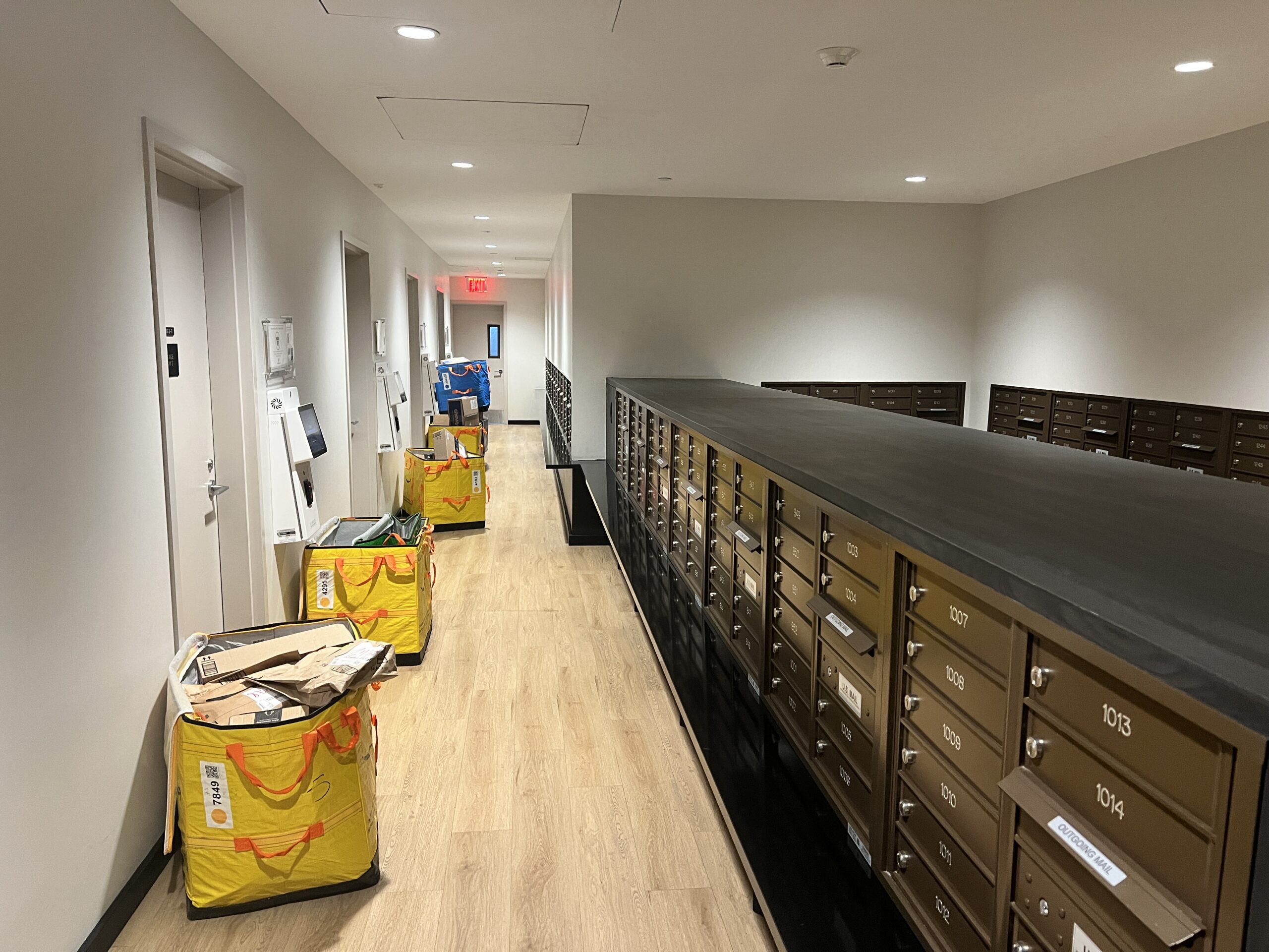 IMG_5127 Apartment mailroom corridor with resident mailboxes and and yellow delivery bags filled with packages