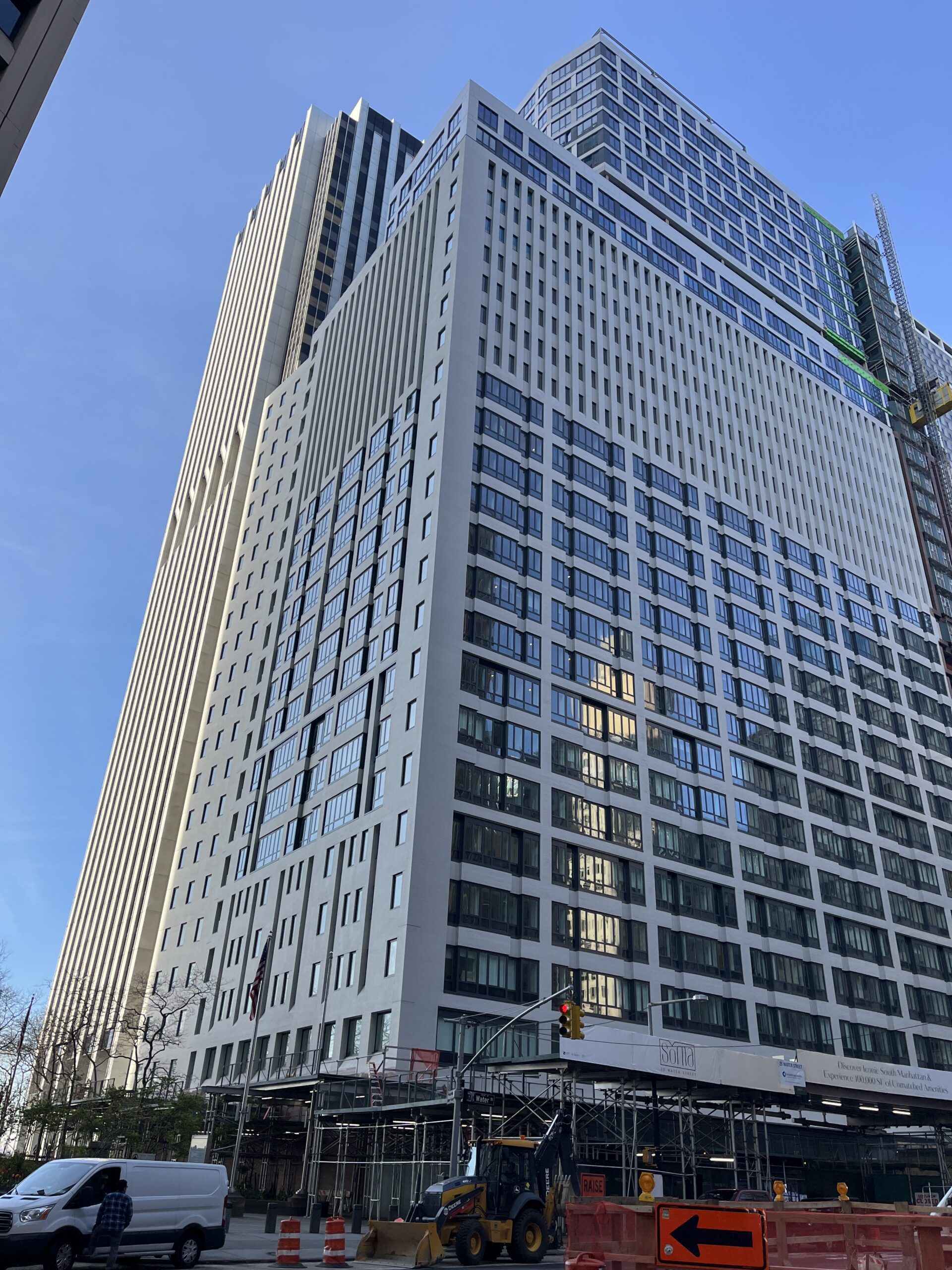 Exterior of a large high-rise multifamily apartment building with construction scaffolding at street level