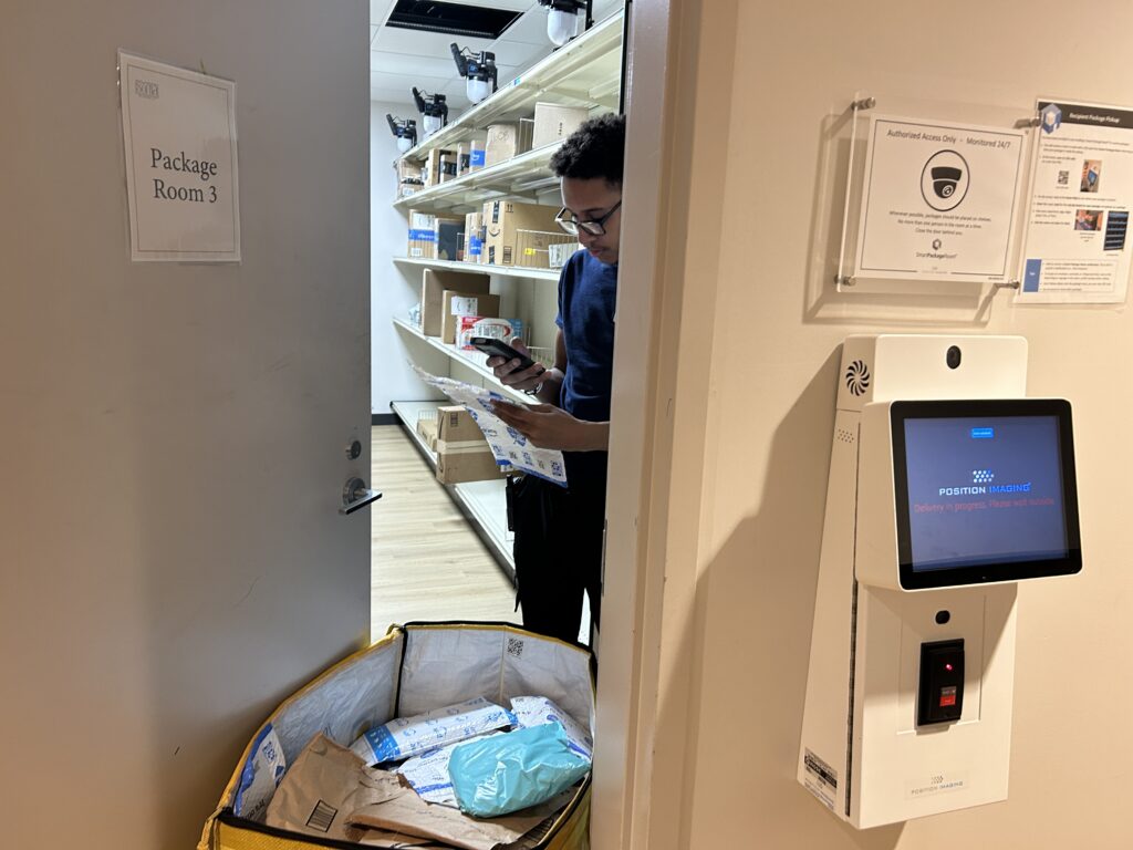 Property staff member scanning a package outside an apartment package room door next to a Smart Package Room kiosk