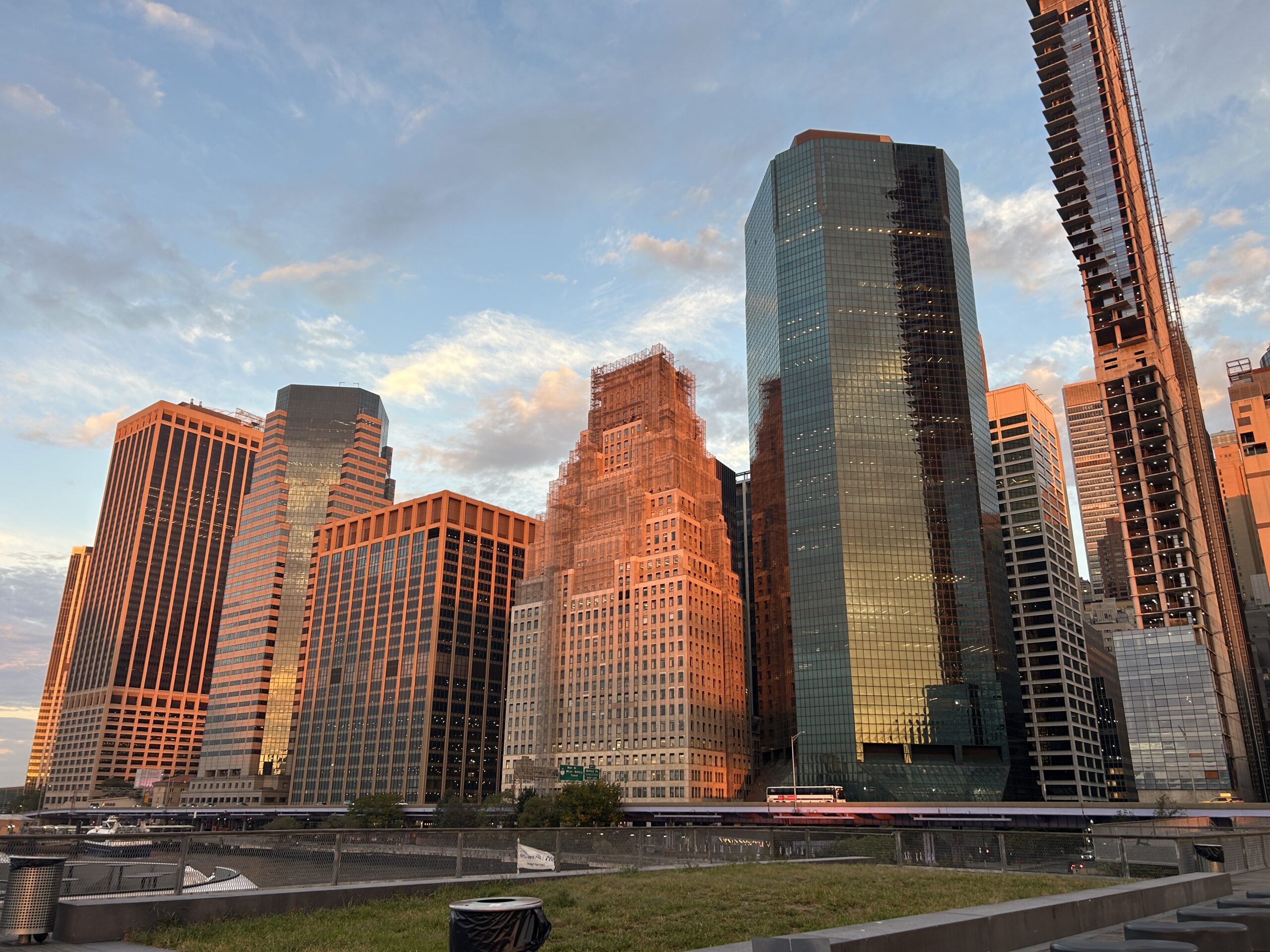 Urban high-rise apartment towers at golden hour along a city waterfront in a dense multifamily district