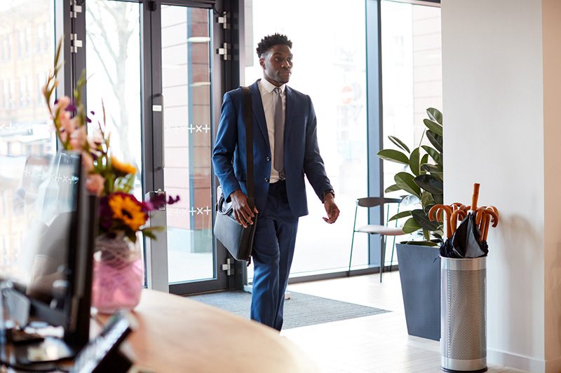 Professional in a suit walking into an apartment lobby at the end of the day to grab a package