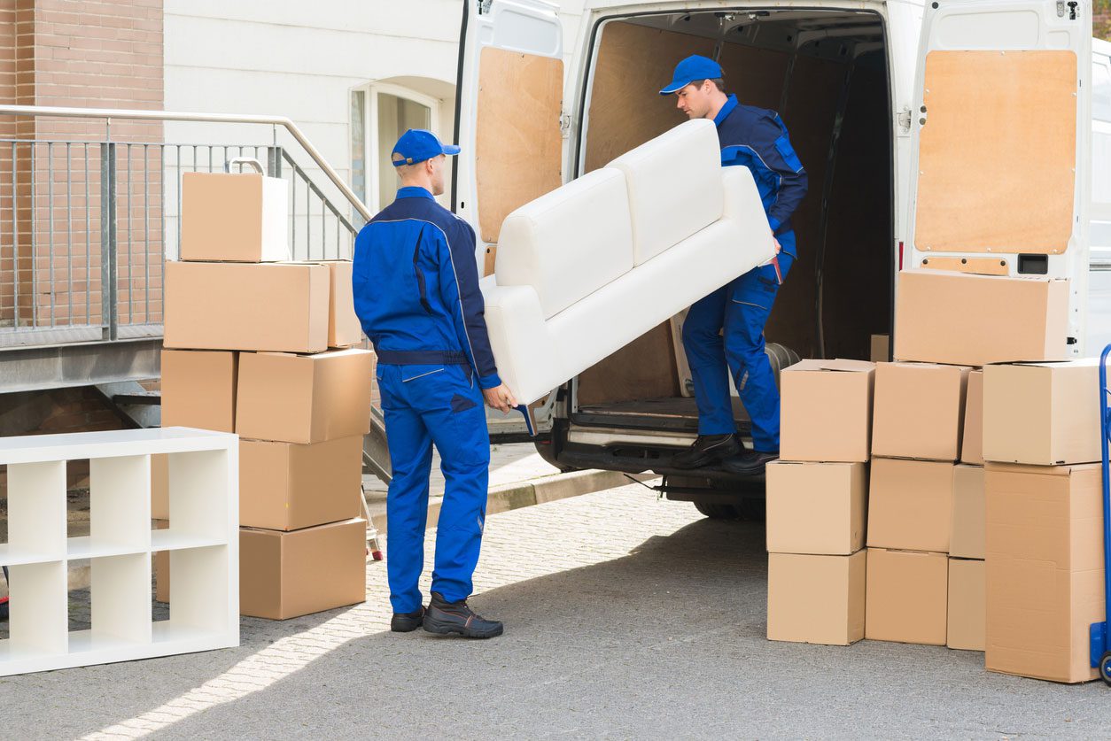 IMG_5127 Two movers in blue uniforms unloading a sofa and stacked boxes from a van during a summer apartment move-in