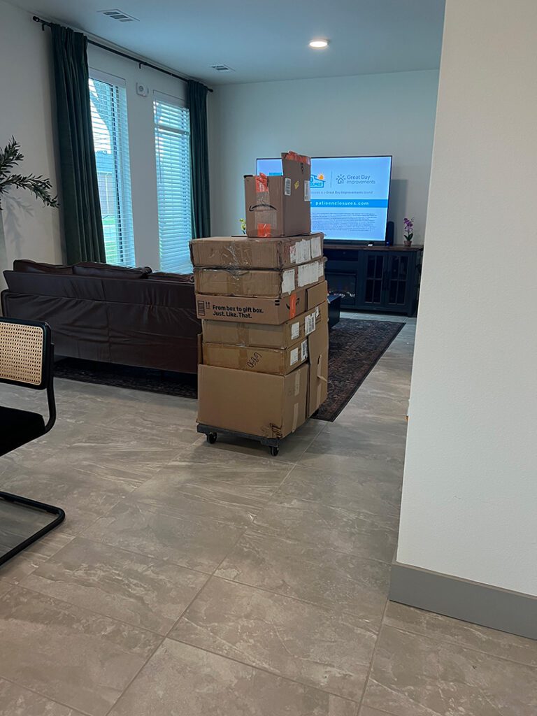 Tall stack of cardboard delivery boxes on a dolly left unsecured in an apartment lobby