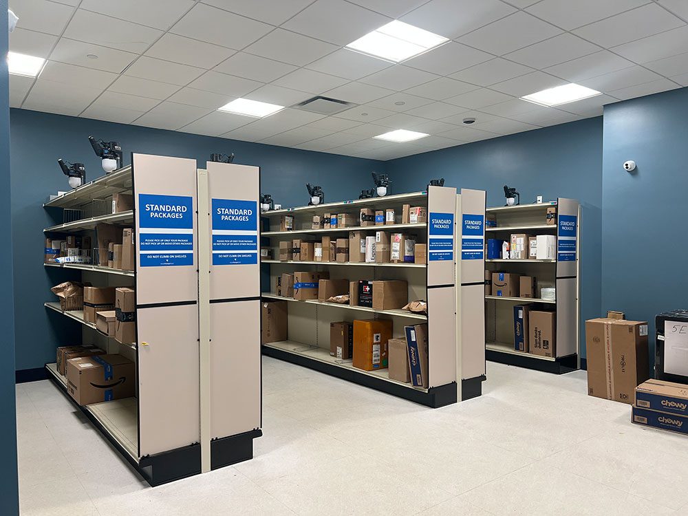 Standard shelves with packages inside a Smart Package Room with Amoeba Modules and presence sensors above the shelving