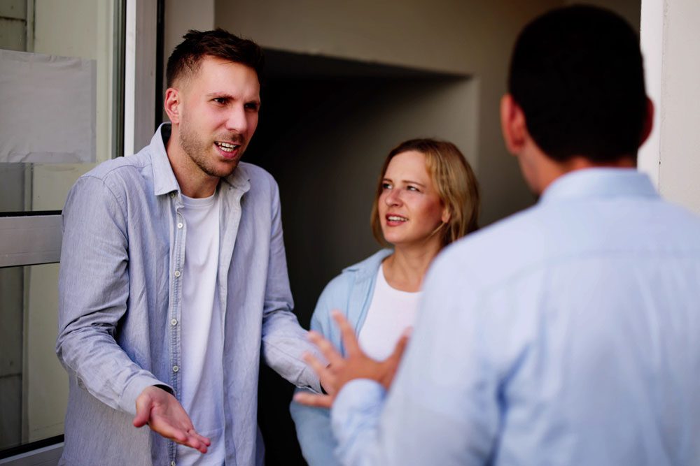 Apartment residents raising a package delivery complaint with property staff outside their multifamily apartment door