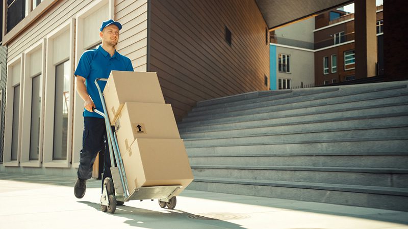 IMG_5127 Courier wheeling stacked parcels into a building where chain of custody for high-value apartment deliveries begins